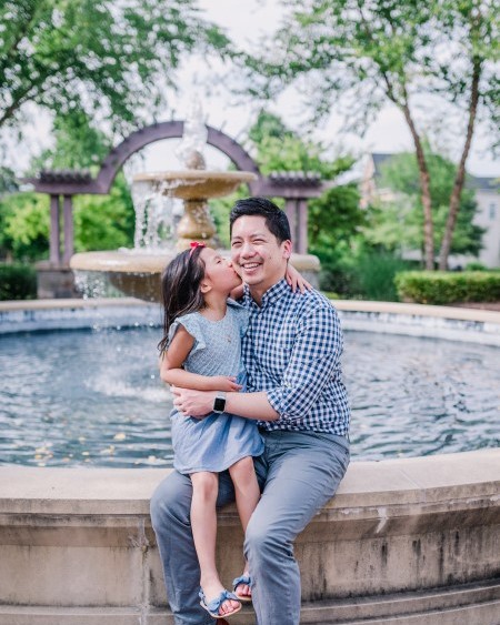 dad holding daughter in front of the water fountain